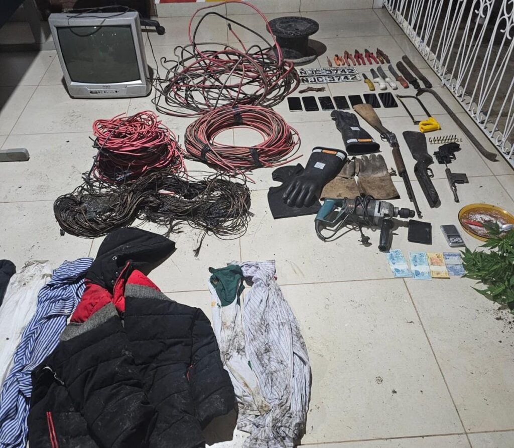 Na madrugada desta sexta-feira (31), a Polícia Civil de Nortelândia, em parceria com a Polícia Militar, prendeu dois indivíduos suspeitos de roubo a uma usina solar e tráfico de drogas. O crime ocorreu por volta de 1h, quando os suspeitos invadiram o local, renderam o segurança e furtaram cerca de 9 mil metros de cabos de cobre e outros materiais.

A operação levou as autoridades a um barraco escondido nos fundos do bairro Buriti, em Diamantino, apontado como ponto de encontro de faccionados. No local, foram apreendidas armas, munições, ferramentas de alta tensão, fios queimados e drogas.

Os indivíduos, com extensa ficha criminal, tentaram fugir, mas foram contidos e encaminhados à delegacia. Ambos seguem presos, enquanto as investigações continuam para identificar outros possíveis envolvidos. A rápida ação policial foi fundamental para recuperar os materiais roubados e desarticular mais um ponto de atividade criminosa na região.